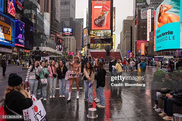 Tourists take a photo with the Naked Cowboy in the Times Square neighborhood of New York, US, on Friday, May 9, 2025. New York City officials cut...