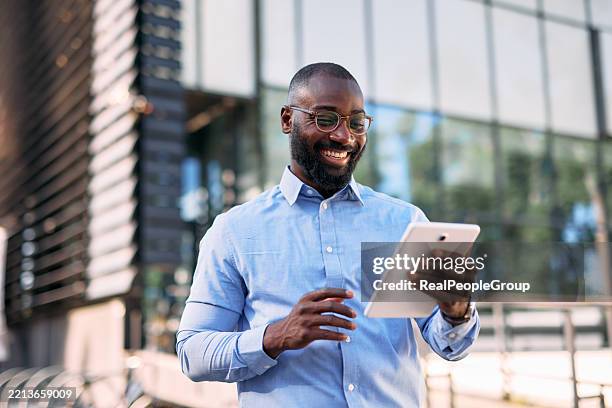 smiling businessman using digital tablet in front of modern office building - ipad bildbanksfoton och bilder