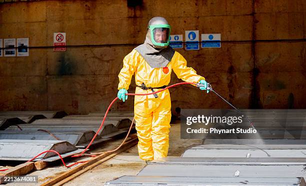 gefahrgutarbeiter im schutzanzug desinfiziert industrielle metalloberflächen - toxisch soziales konzept stock-fotos und bilder