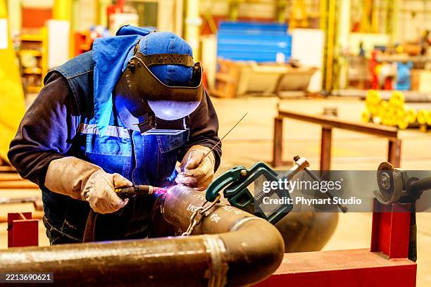 soldador industrial que trabaja en tubería con antorcha de soldadura tig en el taller de la fábrica - soldar fotografías e imágenes de stock