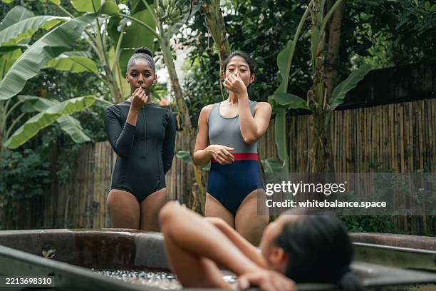 frauen, die die notwendigen schritte für die eisbadtherapie üben und sich mit den fingern die nase zukneifen, um den atem anzuhalten - den sprung wagen stock-fotos und bilder