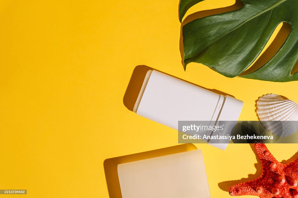 Sunscreen stick on the yellow summer background with tropical leaves and red starfish body care concept, preserving youth