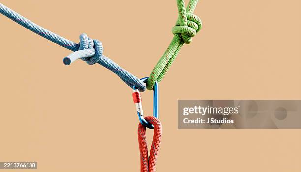 triangular tension: single carabiner pulled by colorful climbing ropes in three directions - karabiner stock-fotos und bilder