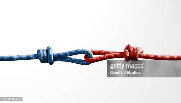 divided forces: red and blue climbing rope knots pulling in opposite directions - effort stock pictures, royalty-free photos & images