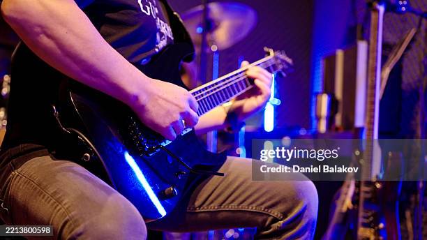 amazing guitar solo with neon lighting, close-up of hands - een instrument plukken stockfoto's en -beelden