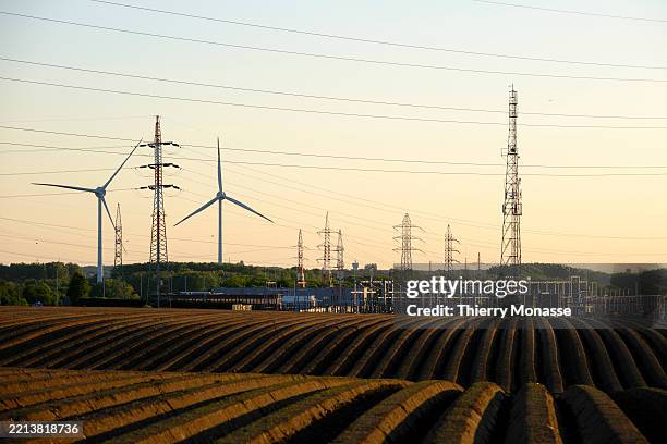Wind turbines, electricity pylons and a plowed field are seen on May 9, 2025 in Courcelles, Belgium. Elia plays a crucial societal role by...
