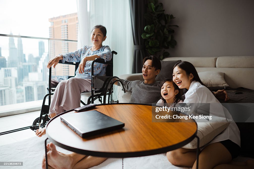 Feliz familia multigeneracional asiática viendo la televisión juntos en casa