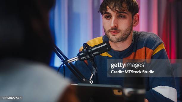 closeup of generation z podcasters collaborating wearing headphones discussing topics during recording session together in home studio at night. - gay social media stock pictures, royalty-free photos & images