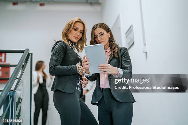 fachleute, die details besprechen, während sie ein tablet im büro verwenden - geschäftsprozess stock-fotos und bilder