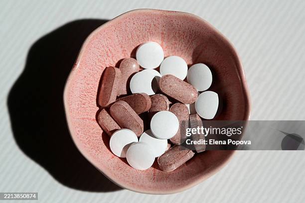small ceramic bowl with heap of pills for support and preventions - hormone stock pictures, royalty-free photos & images