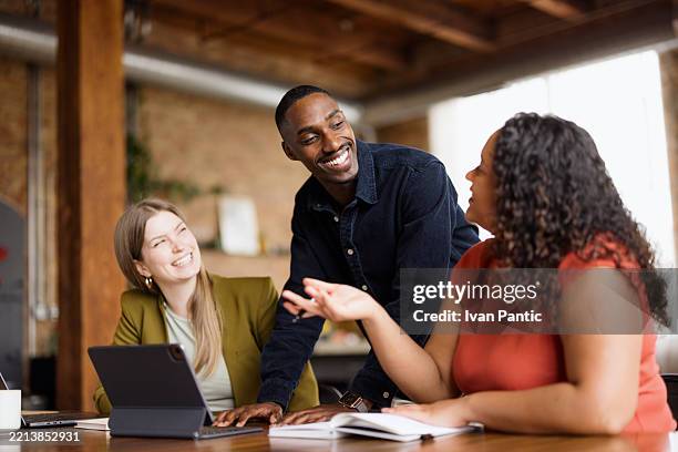 happy black man talking to his female colleagues in the office. - samenwerking stockfoto's en -beelden