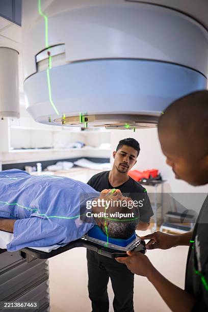 senior man undergoing cancer treatment using advanced linear accelerator technology - deeltjesversneller stockfoto's en -beelden