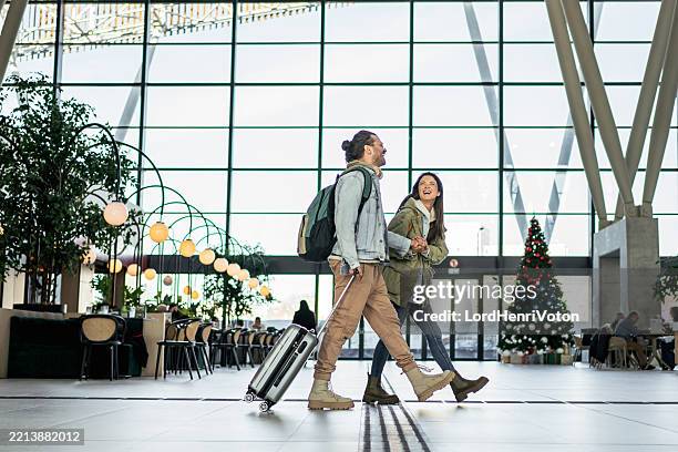 happy tourists couple walking in airport during christmas holidays - happy holidays around the world stock pictures, royalty-free photos & images