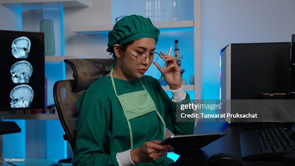 Female surgeon looks at screen with MRI scan with brain Images