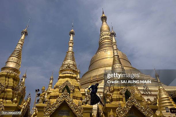 Man cleans and paints a statue as devotees visit Shwedagon Pagoda to mark Buddha's Birthday, which falls on the Full Moon Day of Kasone, in Yangon on...
