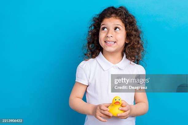 Photo of cute kid girl hold yellow duck look up empty space promo isolated blue color background