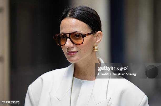 Zina Charkoplia wears white silk top Lily, blazer Bazilika, sunglasses, earrings on May 07, 2025 in Barcelona, Spain.