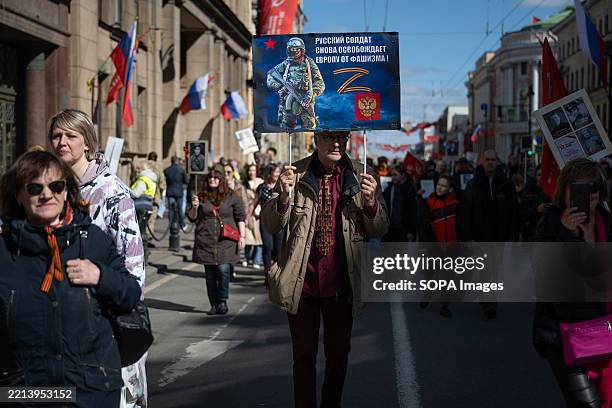 Man carries a placard saying "The Russian soldier is once again liberating Europe from fascism" during the "Immortal Regiment" march on Victory Day...