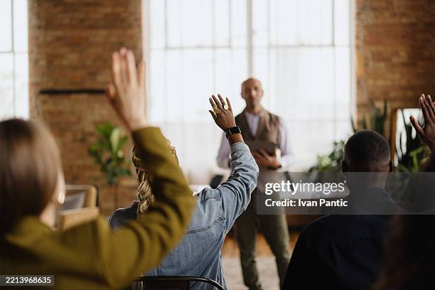 audience raising hands to ask questions during a business conference - vragen en antwoorden stockfoto's en -beelden