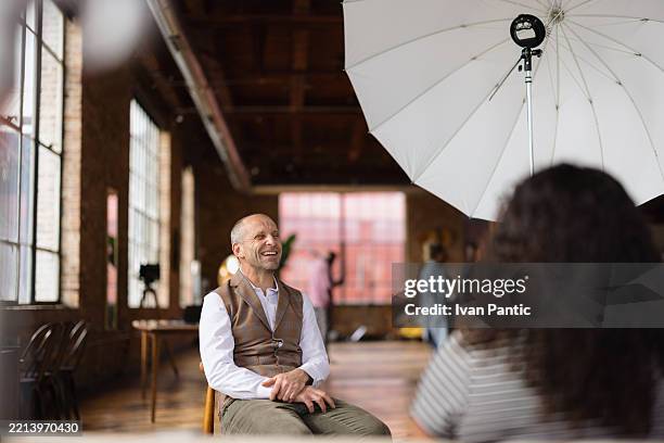 mature businessman laughing during an interview in a loft - media interview stockfoto's en -beelden