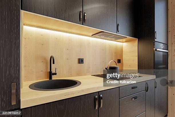 gros plan de la petite cuisine noire compacte dans une cabane en rondins scandinave - parquet flottant photos et images de collection