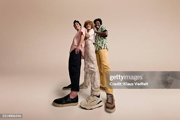 smiling young male friends against beige backdrop - wide angle stock pictures, royalty-free photos & images