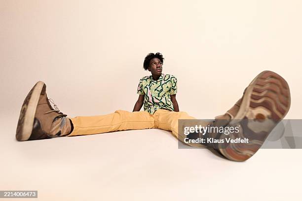 full length of young man sitting with legs apart - wide angle stock pictures, royalty-free photos & images
