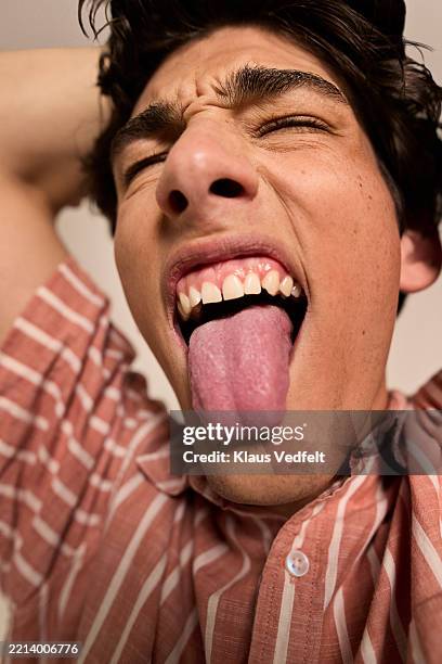 young man with closed sticking out tongue - menschliche zunge stock-fotos und bilder