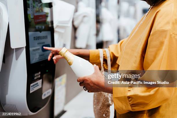 close-up shot of the senior woman with a reusable shopping bag, making mobile payment with her smartphone at super market, scan and pay a bill on a card machine, making a quick and easy contactless payment. nfc technology, tap and go concept. - digital wallet stock pictures, royalty-free photos & images