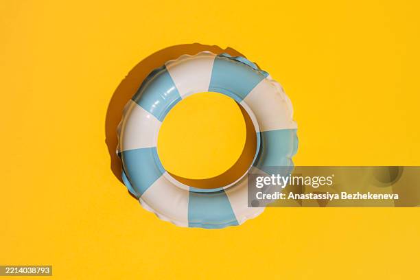 in the center striped white and blue swim ring on a bright yellow summer background - schwimmhilfe stock-fotos und bilder