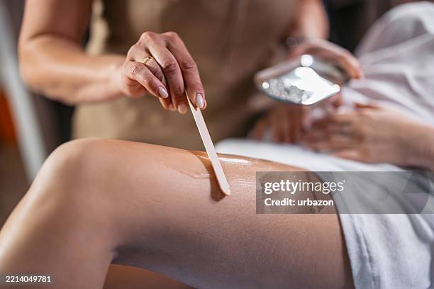 female beautician applying gel on her female client's legs for a laser hair removal procedure at a beauty salon - wax stock pictures, royalty-free photos & images