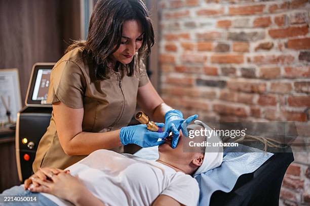 une esthéticienne se tatouant les lèvres d’une cliente dans un salon de beauté - maquillage permanent photos et images de collection