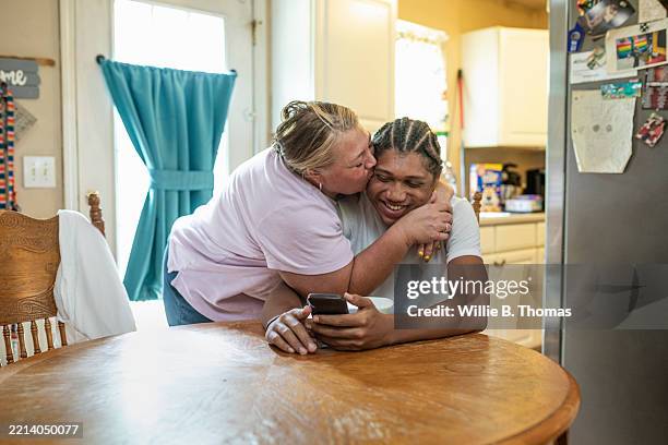 mother kissing teenage son - happy working class family stock pictures, royalty-free photos & images