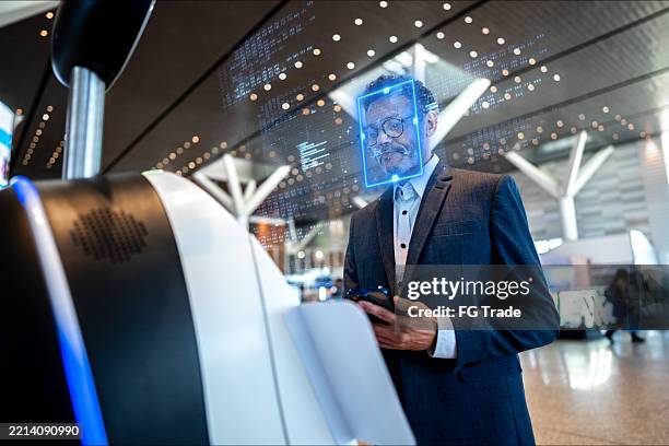 reifer geschäftsmann, der sich beim check-in am flughafen einer gesichtserkennung unterzieht - gesichtserkennung stock-fotos und bilder