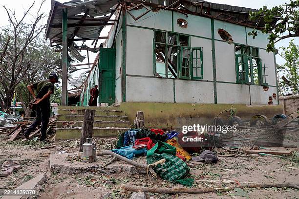 People gather near a school building damaged in a bombardment carried out by Myanmar's military at the Ohe Htein Twin village in Tabayin township,...