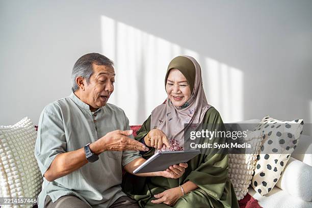senior couple using digital tablet at home - malay people stock pictures, royalty-free photos & images