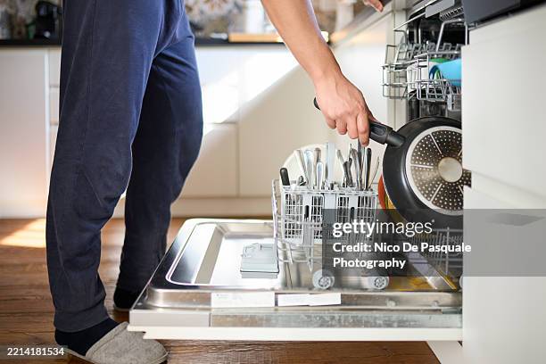 man loading dishwasher at home kitchen - lavastoviglie foto e immagini stock