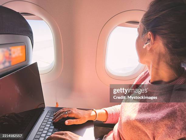 frau, die während des flugzeugflugs an einem laptop arbeitet - fahrzeugkabine stock-fotos und bilder