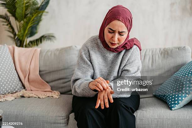 young muslim woman scratching her skin at home - eczema stock pictures, royalty-free photos & images