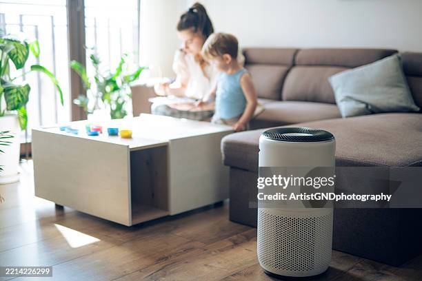 saubere luft zu hause ist wichtig. familie genießt zusammen vor dem luftreiniger. - luftfilter stock-fotos und bilder