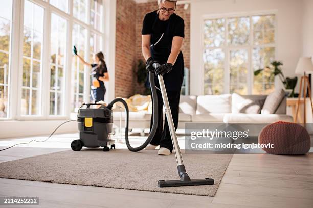 cleaning crew tidying large apartment interior - dienstverlener stockfoto's en -beelden