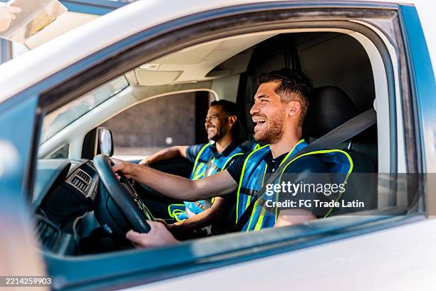 young delivery man talking to coworker and driving van - mini van stock pictures, royalty-free photos & images