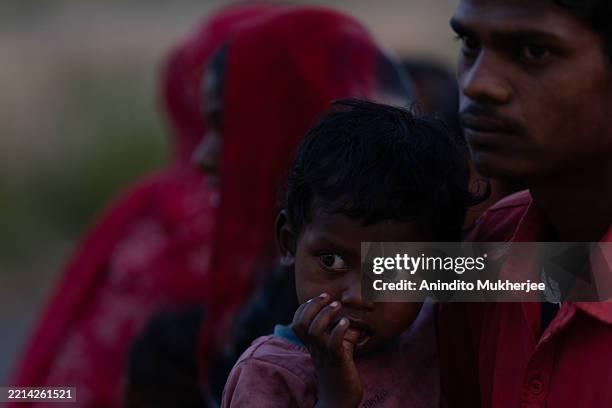Child, carried by his father—a migrant worker who relocated from Dharkal Pind—looks on while taking refuge in a government school, designated as a...