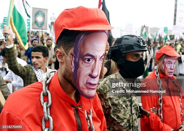 Yemen's Houthi supporters wearing masks depicting the faces of Trump and Netanyahu, chained and standing for trial, participate in a demonstration...