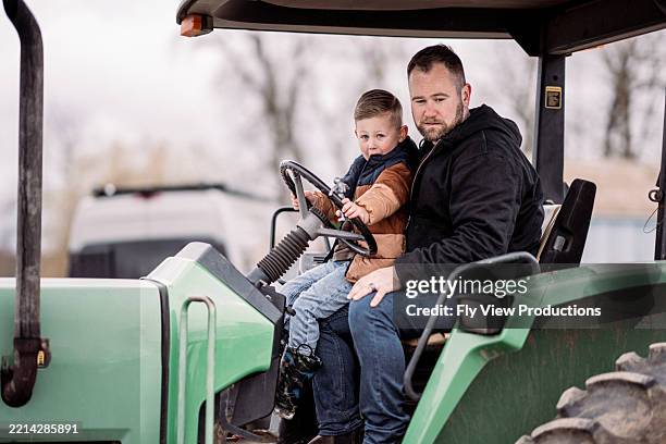 man on the farm driving tractor with his son - rural scene stock pictures, royalty-free photos & images