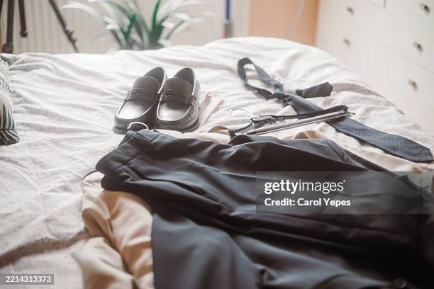 a neatly arranged men´s outfit is laid on a bed, ready to be worn,tailored suit, a matching tie, a polished dress shoes,the clothing suggest preparation for a formal event or special occasion - eleganter schuh stock-fotos und bilder