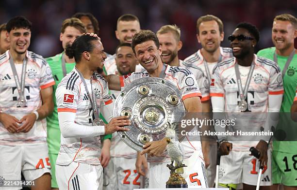 Thomas Mueller and Leroy Sane of Bayern Munich celebrate with the Meisterschale trophy after the teams 2-0 victory in the Bundesliga match between FC...
