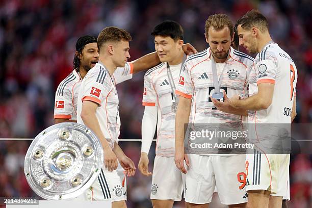 Leon Goretzka of Bayern Munich inspects teammate Harry Kane winners medal, during the trophy presentation after the teams 2-0 victory in the...