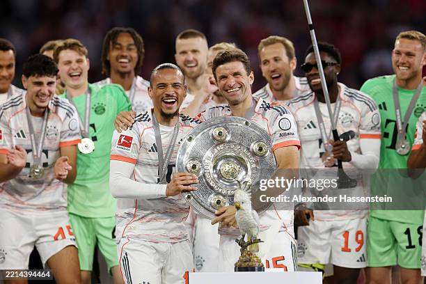 Thomas Mueller and Leroy Sane of Bayern Munich celebrate with the Meisterschale trophy after the teams 2-0 victory in the Bundesliga match between FC...