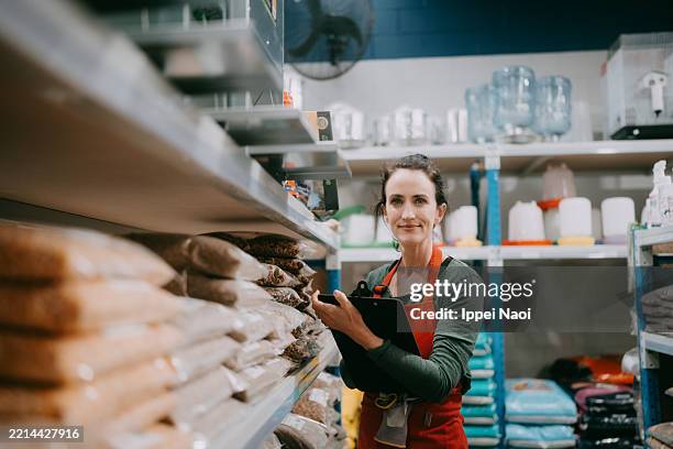 female shop owner checking stock in store - una mujer de mediana edad solamente fotografías e imágenes de stock